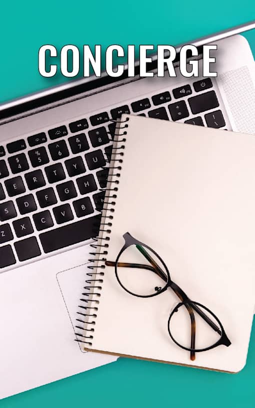A notebook with a pair of glasses on top of it and a laptop in the background with the word "CONCIERGE" written on it.