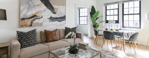 living area with large windows, sofa, coffee table, hardwood floors and view of dining area at the dahlia apartments in washington dc