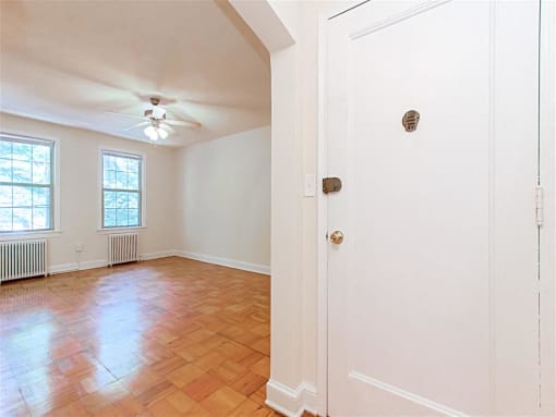 entrance to apartment unit with view of living area with large windows, ceiling fan and hardwood floors at 1400 van buren apartments in washington dc
