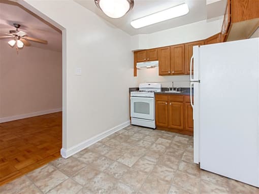 kitchen with oak cabinetry, tile flooring and white appliances at 1400 van buren apartments in washington dc
