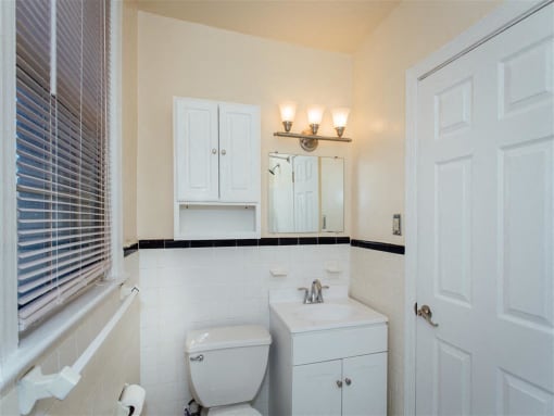 bathroom with toilet, vanity, medicine cabinet, mirror and large window at 2801 Pennsylvania apartments in washington dc