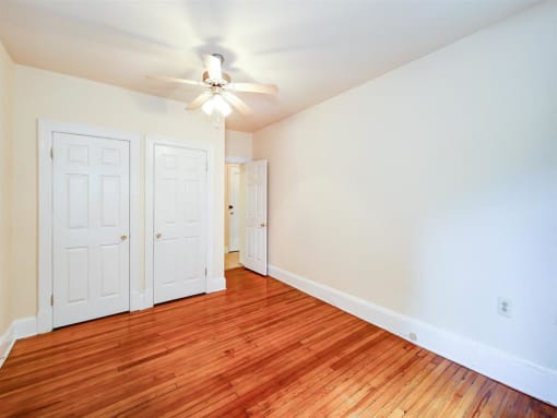 vacant bedroom with hardwood floors, ceiling fan, and large closet at 315 Mount Pleasant apartments in washington dc