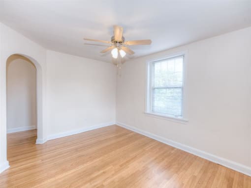 vacant living area with hardwood floors, large windows and ceiling fan at 6100 14th Street apartments in washington dc