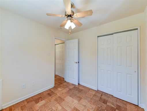 vacant bedroom with hardwood flooring, large closets, and ceiling fan at alpha house apartments in washington dc
