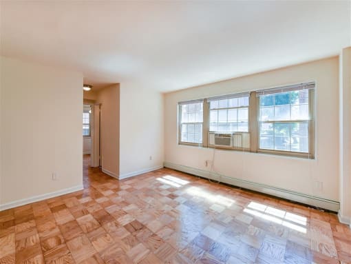 vacant living area with hardwood floors, large windows and view of hallway at alpha house apartments in washington dc