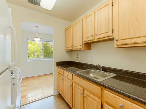 kitchen with tile flooring, refrigerator, gas stove, oak cabinetry, and view of dining area at chillum place apartments in lamond riggs washington dc