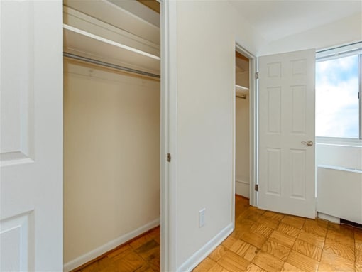 vacant bedroom with hardwood flooring, ceiling fan, window and view of closets at chillum place apartments in lamond riggs washington dc