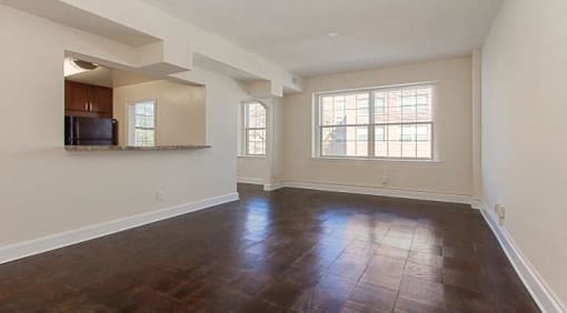 vacant living area with large windows, hardwood floors and view of kitchen at juniper courts apartments in takoma washington dc