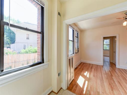 vacant living area with hardwood flooring and large windows at the klingle apartments in washignton dc
