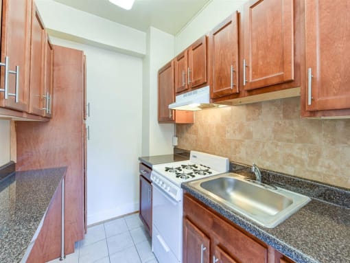 kitchen with wood cabinetry and tile backsplash at the klingle apartments in washignton dc
