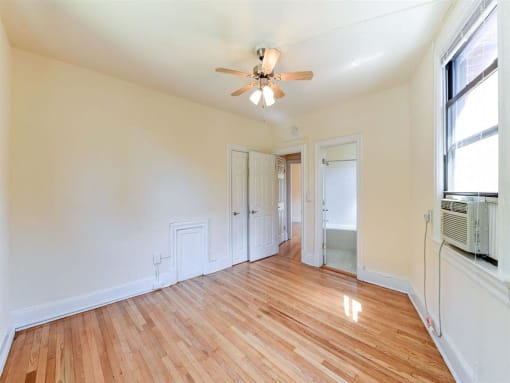 vacant bedroom with hardwood flooring , closet, ceiling fan and view of bathroom at the klingle apartments in washignton dc