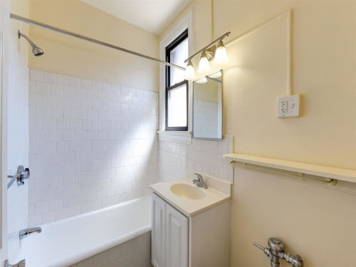bathroom with tub, vanity, mirror and window at the klingle apartments in washignton dc