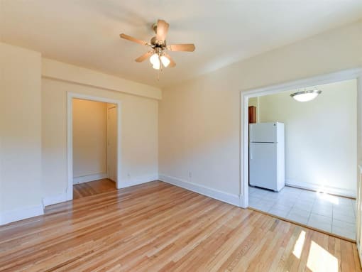 vacant living area with hardwood flooring, ceiling fan and view of kitchen at the klingle apartments in washignton dc
