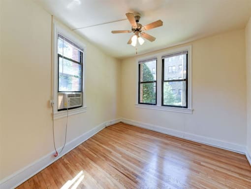 vacant bedroom with hardwood floorings, large windows and ceiling fan at the klingle apartments in washignton dc