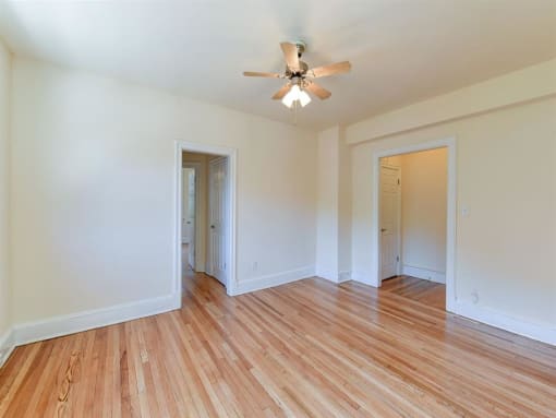vacant bedroom with hardwood flooring and ceiling fan at the klingle apartments in washignton dc