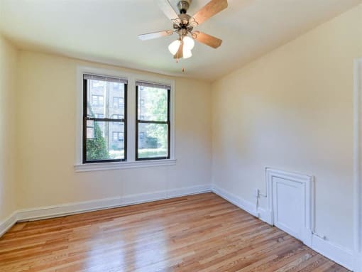 vacant bedroom with hardwood floorings, large windows and ceiling fan at the klingle apartments in washignton dc
