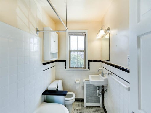 bathroom with tub, toilet, sink, medicine cabinet, mirror and window at the meridian park apartments in columbia heights washington dc