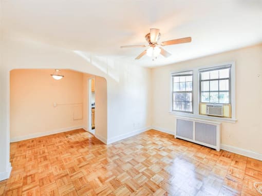 vacant living area with hardwood floors, ceiling fan, window and view of dining area at the meridian park apartments in columbia heights washington dc