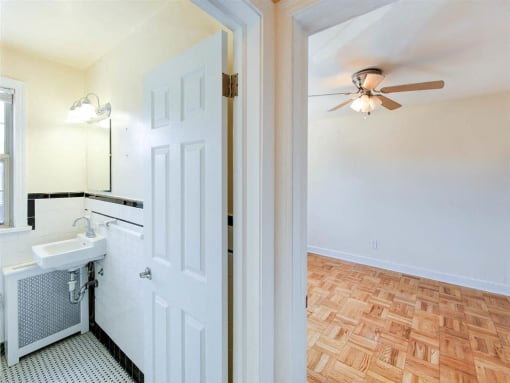hallway view of bedroom with hardwood floors, ceiling fan and bathroom at the meridian park apartments in columbia heights washington dc