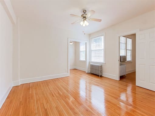 vacant living area with hardwood flooring, ceiling fan, and large windows at parkside apartments in washington dc