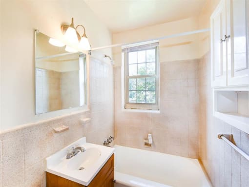 bathroom with tub, vanity, mirror, medicine cabinet and window at randle circle apartments in washington dc