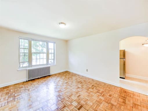 vacant living area with large windows, hardwood floors and view of kitchen and dining areas at randle circle apartments in washington dc