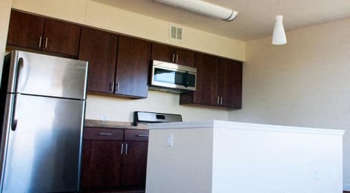 kitchen with espresso cabinetry, stainless steel appliances, and breakfast bar at sheridan station apartments in washington dc