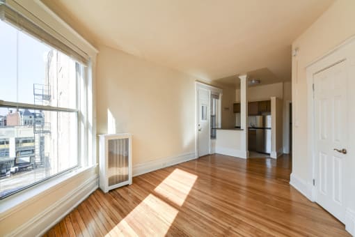 vacant living area with hardwood flooring, large windows and view of kitchen at dupont apartments in washington dc