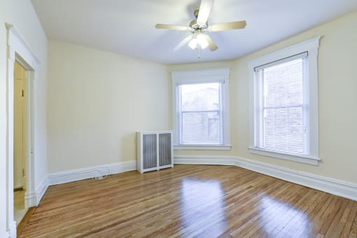 vacant living area with hardwood floors, large windows and ceiling fan at dupont apartments in washington dc