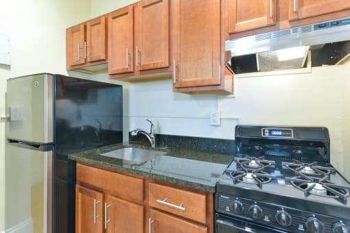kitchen with wood cabinetry, gas stove, and granite countertops at dupont apartments in washington dc