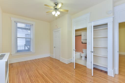 vacant bedroom with hardwood floors, ceiling fan, large closet and view of bathroom at dupont apartments in washington dc