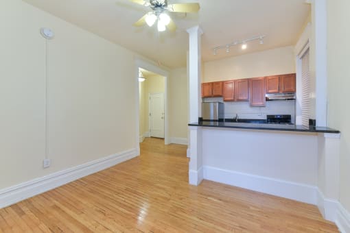 vacant living area with hardwood floors, view of kitchen and ceiling fan at dupont apartments in washington dc