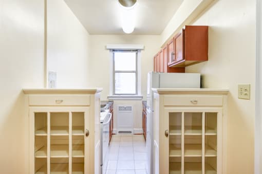kitchen with wood cabinetry, electric range, refrigerator, and window at eddystone apartments in washington dc