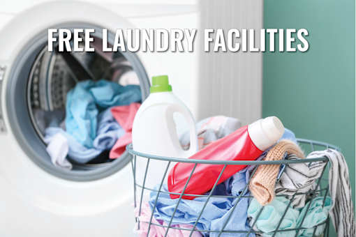 A laundry basket filled with clothes and laundry products in front of a washing machine.