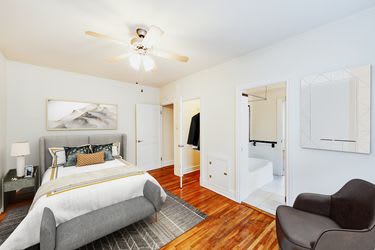 bedroom with bed, nightstand, seating area, large closet, ceiling fan and view of bathroom at hampton courts apartments in washington dc