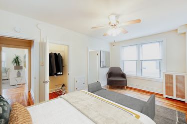 bedroom with bed, seating area, large closet, large window, ceiling fan and view of living area at hampton courts apartments in washington dc