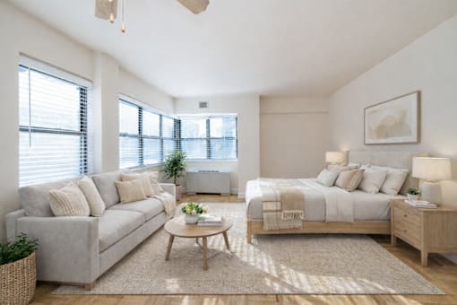 A well-lit bedroom with a large bed, a couch, and a coffee table.