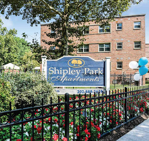 A sign for Shipley Park Apartments is displayed in front of a brick building.