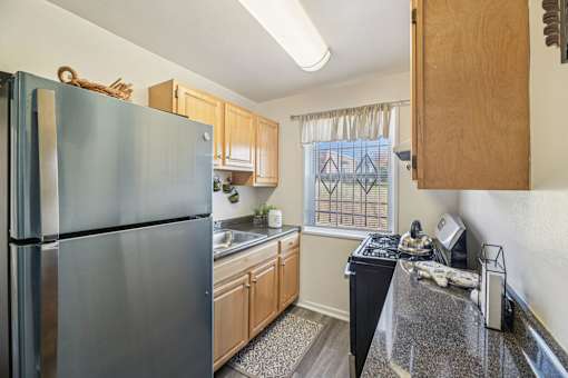 A kitchen with a black fridge and wooden cabinets.