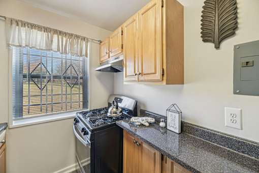 A kitchen with a black stove top oven and wooden cabinets.