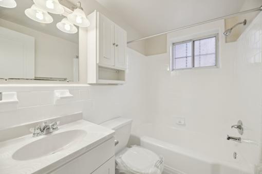 A white bathroom with a toilet, sink, and bathtub.