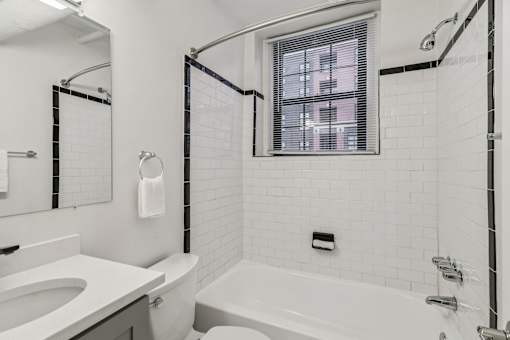 A white bathroom with a tub, sink, and mirror.