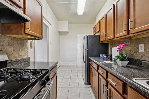 A kitchen with a black refrigerator and wooden cabinets.