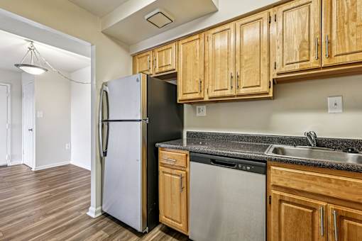 A kitchen with wooden cabinets and a black fridge.
