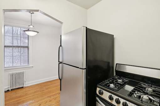 A black refrigerator and stove in a kitchen with a window and radiator.