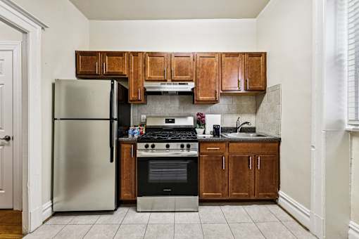 A kitchen with a refrigerator, oven, and cabinets.