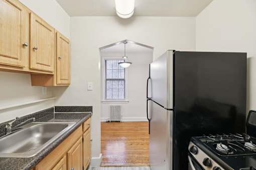 A kitchen with a black refrigerator and a stove top oven.