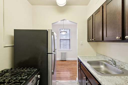 A black fridge in a kitchen with a stove and a sink.
