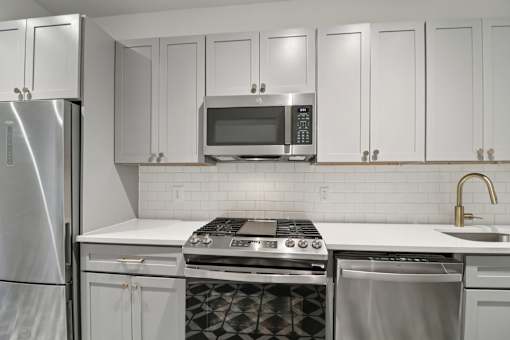A kitchen with white cabinets and a stainless steel refrigerator.