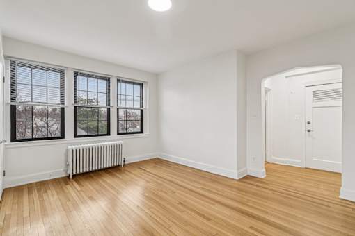 A room with wooden floors and white walls, with a window and a door.